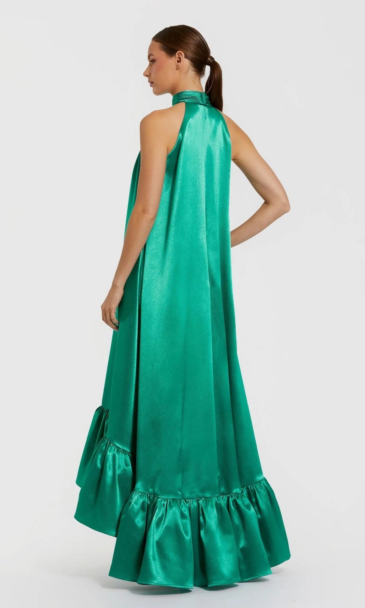 A woman wearing the Mac Duggal 20712 long formal dress—a sleeveless, floor-length green satin gown with a halter neckline and high-low ruffled hem—stands against a plain light background.